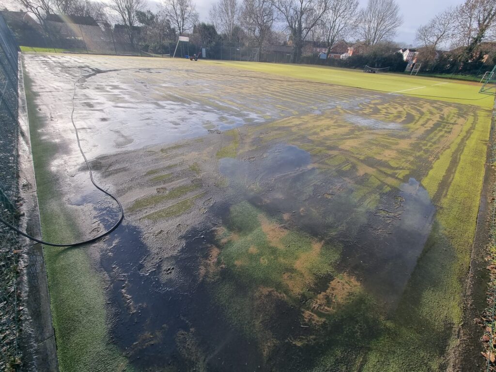 Artificial tennis court maintenance team removing moss, dirt and compacted sand from the surface